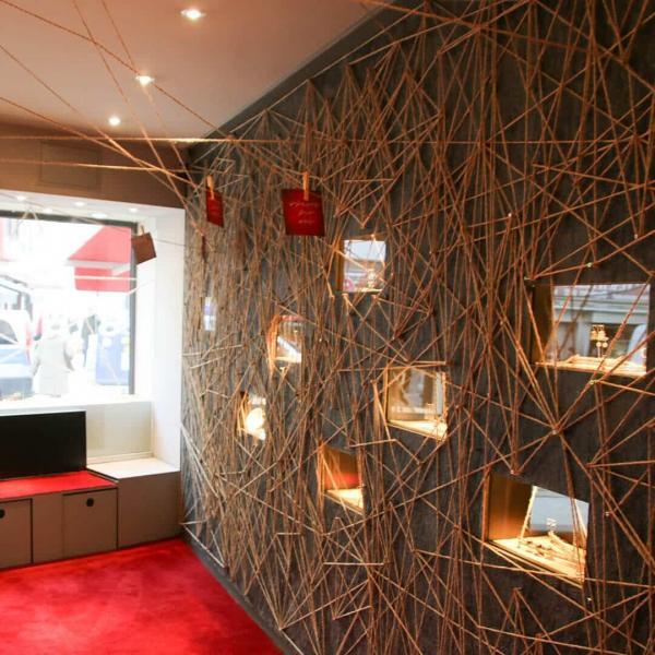 Kunstinstallation mit beleuchteter Vitrinenwand und komplexer Fadenstruktur in der Galerieausstellung „Fest der Liebe“.